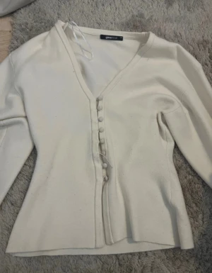 Vit kofta Gina sönder tråd XS  - Supersnygg vit kofta från Gina Tricot med v-ringad hals, tråden går att laga om man är bra på att sy. 