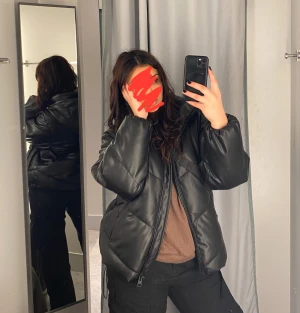 Svart pufferjacka i skinnimitation - Säljer en svart pufferjacka med stor huva och dragkedja. Jackan är varm och skön! Den är från Asos om jag minns rätt, kan dubbelkolla om någon är intresserad! Använt några gånger förra vintern men ser fortfarande helt ny ut. 