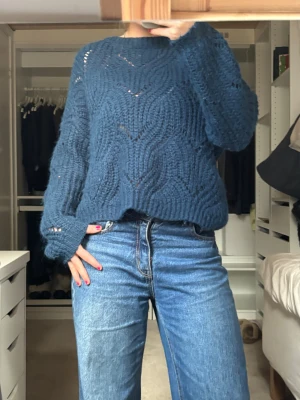 Mörkblå stickad tröja - Säljer en mörkblå stickad tröja från ONLY i storlek S. Tröjan har ett snyggt vågigt hålmönster, rund hals och långa ärmar. Den är loose fit och har ribbade muddar vid ärmslut och nederkant. Perfekt för dig som gillar mysiga och trendiga stickade plagg🩷