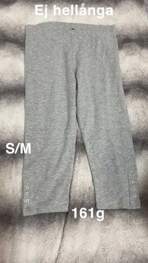 Grå croppade leggings med knappar - Snygga grå leggings i croppad modell med dekorativa knappar längst ner på benen. Perfekta för dig som vill ha ett bekvämt och stilrent plagg till vardags. Mjukt material som känns skönt mot huden.🌸Ej hellånga. Fint använt skick. Storlek s/m