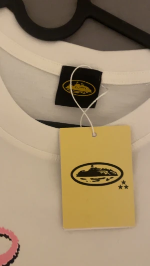 Vit t-shirt med tryck från Submarine - Säljer en vit t-shirt från Submarine med coolt tryck framtill som visar en digital bomb och graffiti i rosa. På ryggen står det 'NO TIME 4 LUV' i svart, fet text. T-shirten har rund hals och korta ärmar, gjord i mjuk bomull. Perfekt för dig som gillar streetwear och statement-plagg.