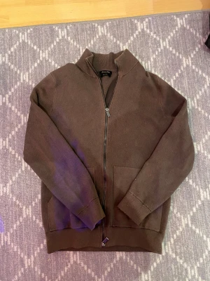 Brun kofta med dragkedja Massimo Dutti - Snygg brun kofta från Massimo Dutti i storlek M. Modellen har hög krage, hel dragkedja framtill och två fickor. Materialet är stickat och känns mjukt och skönt. Perfekt för lager-på-lager under höst och vinter.