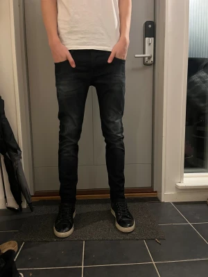 Replay anbass jeans - Jag säljer ett par stilrena Replay anbass jeans i storleken 30 30. Dom har en svart färg med lite tvätt mot knäna. Perfekt för dig som vill ha ett par snygga och exklusiva jeans nu till vintern. Priset är ej hugget i sten. Hör av dig vid intresse