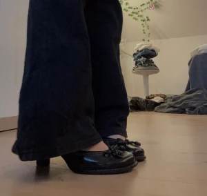 Svarta pumps från Clarks med rosett - Säljer ett par svarta pumps från Clarks med rund tå och låg klack. Skorna har en söt rosettdetalj framtill och kontrastsömmar längs kanten. Tillverkade i skinn med beige insida, passar perfekt om du gillar klassisk och stilren vibe.