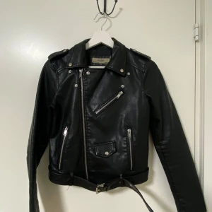 Svart skinnjacka från AFTF BASIC - Skinnjacka - väldigt snygg, stilren och bekvam. I gott skick, sitter fint. Det finns lite slitage och en avbruten hängögla, men det syns knappt och paverkar inte utseendet. Skick: bra Kan skickas snabbt