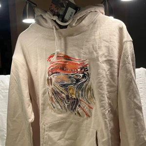 Derschutze Painter Hoode - En unik beige Derschutze-hoodie  På framsidan finns ett broderi i form av ”Skriet”  Tröjan är ny, med etiketter och originalförpackning.  Storlek: M