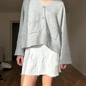 Vit kortkjol från Esprit - Vit kortkjol från Esprit i bomull med råa kanter och fickor. Kjolen har sömdetaljer och små bälteshällor i midjan. Perfekt för en fräsch och avslappnad look under varmare dagar.