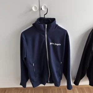 Palm Angels Zip Tröja - Säljer nu min mörkblå Palm Angels tröja, tröjan är i absolut nyskick. Helt äkta!!!! CLG kod fås skickat privat vid intresse:) storleken är M! Priset kan självklart diskuteras:)