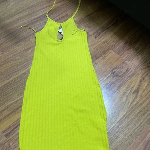 Gul ribbad klänning från Bik Bok - Snygg gul ribbad klänning från Bik Bok med smala axelband och en cool cut-out detalj framtill. Klänningen är ärmlös och har en kroppsnära passform som ger en fräsch och trendig look. Perfekt för varma dagar och somriga vibes.