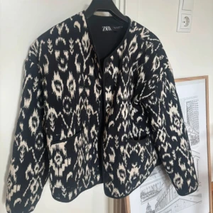 Svartvit mönstrad jacka från Zara - Snygg svartvit jacka från Zara med unikt mönster och två fickor framtill. Jackan har en rak passform och är perfekt för dig som vill sticka ut med en cool look. Materialet känns mjukt och bekvämt, och den har långa ärmar.