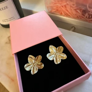 Guldiga blomformade örhängen - Super söta guldiga örhängen і blomform Helt nya såklart. Asken ingår ej