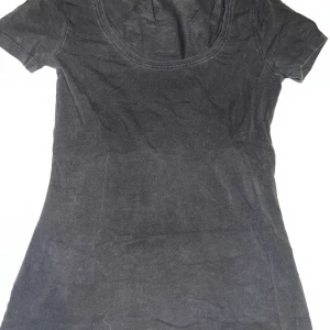 Tshirt - En enkel svart topp från Anna Field med rund halsringning och korta ärmar. Modellen är figurnära, perfekt för en clean och stilren look. Den är helt svart, men blev skum i kameran. Inga defekter 