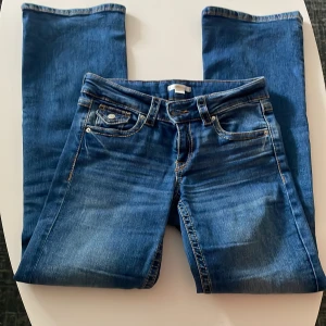 Blå bootcut jeans Lågmidjade  - Snygga blå jeans med bootcut-modell och klassisk tvätt. Jeansen har fem fickor, kontrastsömmar och en något utsvängd benslut. Perfekta för dig som gillar en tidlös och avslappnad stil.