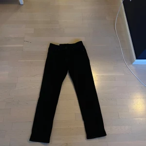 Svarta jeansbyxor i rak modell från HM - Säljer ett par svarta jeansbyxor med klassisk femficksdesign och rak passform. Byxorna har normal midja och är tillverkade i ett mjukt jeanstyg som passar perfekt till en avslappnad stil.
