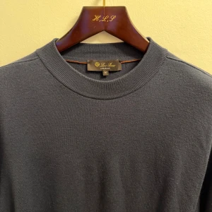 Loro Piana tröja  - Säljer en stilren mörkblå tröja från Loro Piana i 100% virgin wool. Tröjan har rund halsringning, ribbade muddar och lång ärm. Perfekt för dig som gillar klassisk och clean look med premiumkänsla.