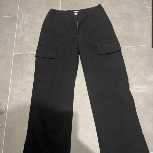 Svarta cargobyxor från Zara, strl 36 - Svarta cargobyxor från Zara i storlek 36. Byxorna har raka ben, flera stora fickor på sidorna och bak, samt klassisk cargostil. Tillverkade i bomullsmaterial för en skön känsla och avslappnad look.