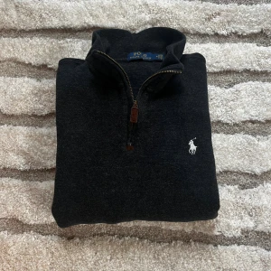 Polo Ralph Lauren Stickad Quarter-Zip: M/S - Säljer en super fin Stickad Quarter-Zip ifrån Polo Ralph Lauren. Tröjan är i storlek M men sitter som en S. Tröjan är mörk grå/svart. 👍 Hör av er vid fler funderingar😊