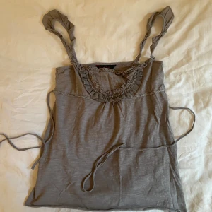 Söt babydoll topp - Grå topp som kan knytas bakom ryggen. Köpt secondhand därför Lloyd sliten men inga större defekter. 