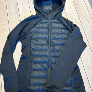 Peak Performance Down Hood W Hybridjacka  - Säljer en jättefin Peak Performance Down Hood W Hybridjacka i nyskick då den tyvärr var för stor. Färg: Svart Storlek: Large (men små i storlekarna), skulle säga den passar storlek 36-40 Material: Dun