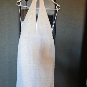 Vit virkad halterneckklänning Gina Tricot - Supersöt vit virkad halterneckklänning från Gina Tricot. Klänningen har djup v-ringning, öppen rygg och dragkedja bak. Perfekt för sommarens varma dagar och har en lätt, luftig känsla tack vare det virkade materialet.