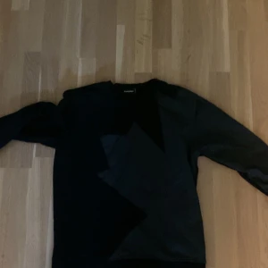 Svart sweatshirt från Dsquared2 - Cool svart sweatshirt från Dsquared2 med grafiskt mönster framtill. Tröjan har lång ärm och klassisk passform, perfekt för dig som gillar streetstyle. Stor Dsquared2-logga på ryggen ger en extra touch. Materialet känns mjukt och bekvämt.