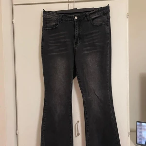 Svarta bootcut jeans - Snygga svarta jeans med bootcut-modell och diskreta slitningar framtill. Jeansen har klassisk femficksdesign, hällor för bälte och stängs med knapp och dragkedja. Materialet är stretchigt jeans för en bekväm passform.