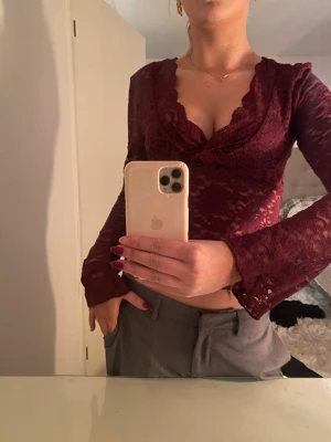 Vinröd spetsblus med v-ringning - Säljer en vinröd långärmad topp i spets från Gina. Fina utsvängda ärmar 🫶🏼Storlek M, sitter som en S