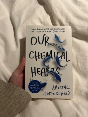 Our Chemical Hearts av Krystal Sutherland - En engelskspråkig pocketbok med titeln 'Our Chemical Hearts' av Krystal Sutherland. Omslaget är vitt med blå fiskar och svart text. Boken handlar om tonårskärlek och känslor, och har blivit en Amazon Original Movie. Perfekt för dig som gillar romantik och drama.