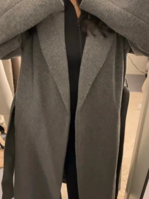 Grå lång kappa med skärp - Söt kappa från missäy. Aldrig använd då jag inte föredrar grå. Super fin och i jättefint skick!🤍