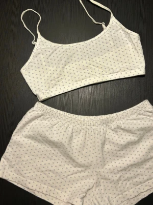 Brandy Melville Set - Sött tvådelat underklädesset i vitt med små ljusblå hjärtan. Setet består av en topp med smala axelband och ett par shorts med resår i midjan. Mjukt och bekvämt material, perfekt för att chilla hemma.