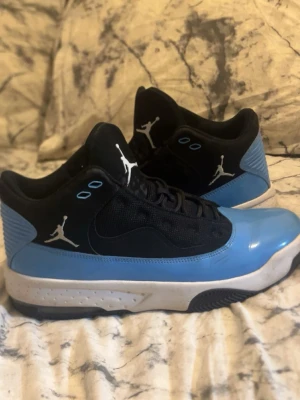 Jordan sneakers svart/blå - Snygga Jordan sneakers i svart och ljusblått med vit sula och klassisk Jumpman-logga på sidan och plösen. Ovandelen är i mesh och läder, vilket ger både stil och komfort. Perfekta för dig som vill sticka ut med en sportig look.