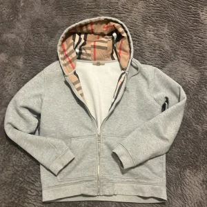 Burberry zip hoodie  - Säljer denna burberry zip för har växt ur den. Storleken är XL men skulle säga att den passar mer L. Skicket är bra, ett litet slitage(se bild 3) men annars i ett väldigt bra skick. Har ni några frågor är det det bara att höra av sig