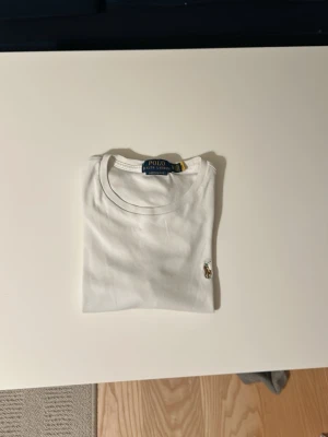 Vit t-shirt från Polo Ralph Lauren - Klassisk vit t-shirt från Polo Ralph Lauren med broderad logga på bröstet. Modellen är custom slim fit och har rund halsringning. Perfekt basplagg med stilren design och diskret detalj. Använd ett fåtal gånger men inga defekter. Levererar inom 48h👍