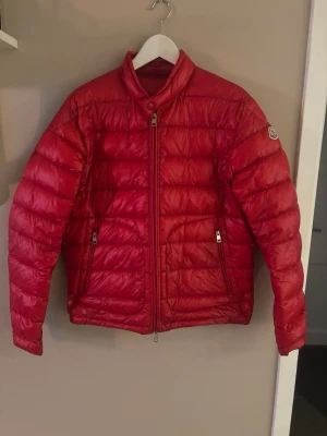 Röd dunjacka från Moncler - Säljer nu min riktigt snygga moncler jacka som är storlek 3 som motsvarar L men skulle säga den sitter som M,L. Den är i väldigt gott skick. De är bara att höra av sig om några frågor. Jackan är äkta!! Priset är inte helt fast