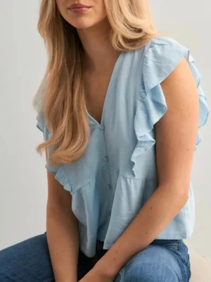 Ljusblå volangblus med knappar - Supersöt ljusblå blus med volangdetaljer längs axlarna och knäppning framtill. Köpt från Nelly för 329kr, har använt typ 3 gånger så i bra skick förutom lite skrynklig men går att fixa. Skulle säga lite liten i storleken särskilt vid brösten så mer mot en xs än S. 