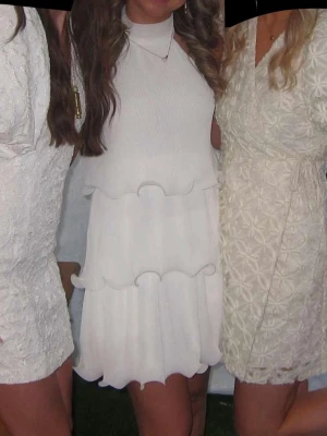 Vit volangklänning med öppen rygg - Superfin vit kortklänning med volanger och öppen rygg. Klänningen har ärmlös design och rund halsringning. Perfekt för somriga tillfällen och studentfirande. Materialet känns lätt och luftigt. Använde inte under flaket på studenten så den är fortfarande jätte fin vit och utan fläckar 
