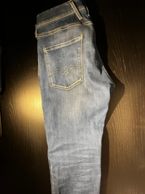 Blå jeans från Replay  - Säljer ett par snygga blå jeans från Replay med klassisk femficksmodell och ljusa slitningar. Jeansen har gul kontrastsöm och en smal passform som sitter riktigt bra. Inga deffekter 🙌passar perfa på mig som är ca 183