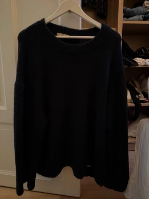Marinblå stickad tröja Gina Tricot L - Mysig svart stickad tröja från Gina Tricot i storlek L. Tröjan har en enkel rund halsringning och långa ärmar. Perfekt för kyliga dagar och enkel att styla med olika outfits.
