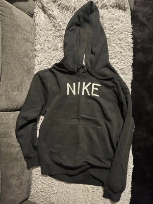 Nike tröja  - Svart hoodie från Nike med vit NIKE-logga. Bekväm och stilren modell 