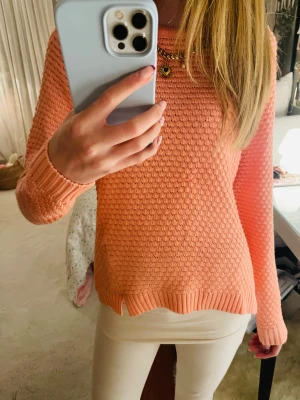 Korallrosa stickad tröja med struktur - Säljer superfin korallrosa stickad tröja med strukturerat mönster och rund hals. Tröjan har långa ärmar och ribbade muddar vid ärmslut och nederkant. Tröjan är ifrån Cubus.