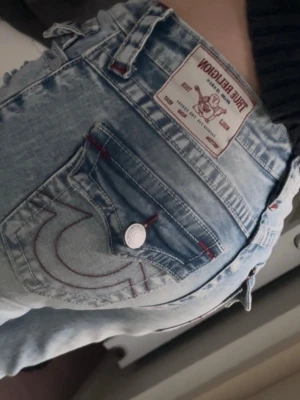 True Religion bootcut jeans - Säljer ett par ljusblå bootcut jeans från True Religion. Väldigt bra skick i princip nytt förutom att en knapp saknas på en av bakfickorna. Inget som stör dock! Har hål på knäna och mörkröda sömmar på fickorna💕💕
