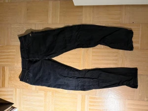 Svarta G-star raw jeans med dragkedja - Säljer ett par svarta jeans från Diesel med snygga detaljer som dragkedja på bakfickan och klassisk g star raw logga på linningen. Jeansen har en rak passform och är tillverkade i slitstarkt denim. 