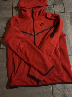 Nike tech fleece - Säljer nu min röda nike tech fleece pga att den ej används längre. Den har en liten tråkig kedja som kan vara jobbig att stänga ibland plus en liten skada vid en ficka och där man hänger up tröjan inuti därav priset. Hör av er om ni har några funderingar eller vill ha mer bilder😀.