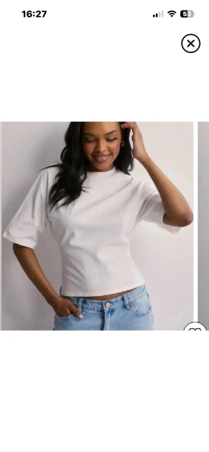 Vit croppad topp med knyt i ryggen - Säljer en stilren vit croppad topp med korta ärmar och snygg knytning i ryggen. Toppen har en rak passform och är tillverkad i mjukt bomullstyg. Perfekt att matcha med jeans eller kjol för en fräsch look.