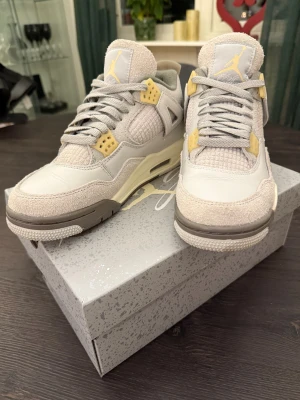 Nike Air Jordan 4 craft Photon Dust EUR 39 - Nike Air Jordan 4 Retro i färgen Photon Dust. Snygga sneakers med grå och beige toner, detaljer i ljusgul och klassisk Jumpman-logga. Ovandel i mocka och textil, meshpaneler och snörning. Perfekt för dig som gillar stilrena och unika sneakers. Äkta och köpta hos merchsweden. Använda 3-5 gånger och i nytt skicka. Inga skador, repor mm.