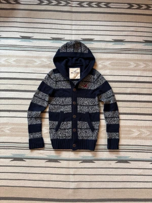 Stickad hoodie med knappar från hollister - Sjukt snygg, eftertraktad o unik cardigan från hollister. Blå randig utan defekter!