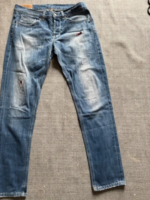 Blåa Dondup jeans - Säljer ett par Dondup jeans i ljusblå tvätt med slitningar och lagade detaljer. Klassisk femficksmodell med Replay-logga på bakfickan och kontrastsömmar. Jeansen har en slim passform och är tillverkade i stretchigt bomullsmaterial.  Dm för frågor! 🙌
