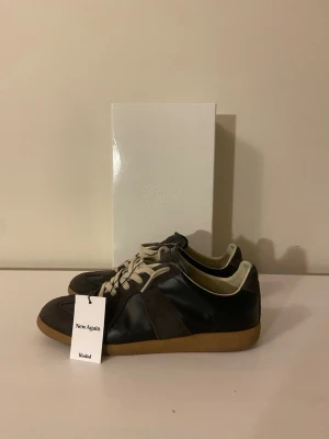 Maison Margiela Gats - Tvär feta Maison margiela gats i brun färg. De är i bra skick och har endast en defekt och det är på utsidan av den vänstra skon. Lädret har förstörts lite där. Förutom det är de i riktigt bra skick. Kan sänka priset vid en snabb och enkel affär!