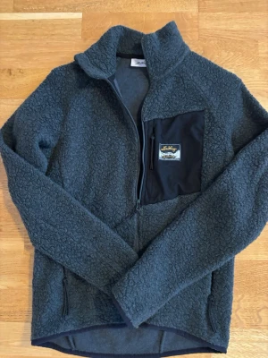 Lundhags tröja i ull, XS - Tröja från Lundhags i Flok Wool. Storlek XS.  Mycket bra skick, sparsamt använd. Varm och bekväm med dragkedja och bröstficka.