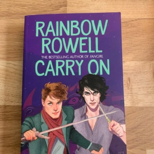 Carry On - En färgstark och spännande bok med magi, monster och äventyr. Perfekt för dig som gillar fantasy och berättelser om unga hjältar. Omslaget visar två karaktärer med svärd och trollstav, och boken utspelar sig på en magisk skola. Passar ungdomar och unga vuxna som vill ha något roligt och magiskt.
